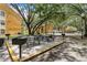 Outdoor grill area with charcoal grills and picnic tables shaded by mature trees at 5263 Images Cir # 306, Kissimmee, FL 34746