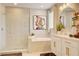 Well-lit bathroom with tan tile walls, a glass shower, a tub, and double sink vanity at 5310 Teirgarten St, St Cloud, FL 34771