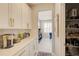 Hallway between kitchen and living room featuring white cabinets, gold hardware, and tiled backsplash at 5310 Teirgarten St, St Cloud, FL 34771
