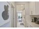 Hallway view with white cabinets, gold hardware, tiled backsplash and open access to dining area at 5310 Teirgarten St, St Cloud, FL 34771