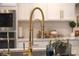 Close-up of a gold kitchen faucet, complemented by white cabinets and a modern countertop at 5310 Teirgarten St, St Cloud, FL 34771