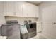 Functional laundry room equipped with modern washer and dryer, ample storage, and a utility sink for convenience at 5310 Teirgarten St, St Cloud, FL 34771