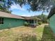 View of the backyard and rear of the house, with large windows, plants and green exterior paint at 6740 Odoniel W Loop, Lakeland, FL 33809