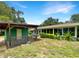 View of the backyard featuring a green house, a partially-covered porch, and lush landscaping at 6740 Odoniel W Loop, Lakeland, FL 33809