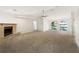 Bright living room features a brick fireplace, neutral carpet, ceiling fan, and arched windows overlooking the backyard at 6740 Odoniel W Loop, Lakeland, FL 33809