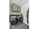 Functional laundry room featuring modern washer and dryer, stylish green cabinets, and decorative elements at 7809 Altavan Ave, Orlando, FL 32822