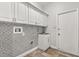 Laundry room featuring mosaic tile backsplash, white cabinetry, and a utility sink at 917 Southern Oak Ln, Apopka, FL 32712