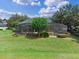 Landscaped backyard with a screened enclosure, trees, and green lawn at 1224 Northern Way, Winter Springs, FL 32708