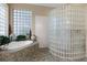 Bright bathroom features a glass block shower, soaking tub, neutral tile, and a large window at 1224 Northern Way, Winter Springs, FL 32708