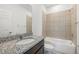 Well-lit bathroom featuring a granite countertop vanity and tiled shower-tub combination at 1323 Wood Line Dr, Deland, FL 32720