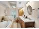 Bathroom featuring double sinks, mirrors, and a soaking tub under an arched window at 14634 Astina Way, Orlando, FL 32837