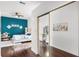 Bedroom with hardwood floors and a mirrored closet door, showing a glimpse into another room at 14634 Astina Way, Orlando, FL 32837
