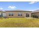 Back exterior of home showing windows, sliding glass door, and fenced yard at 1797 Sundance Chase Rd, Minneola, FL 34715