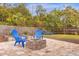 Backyard features a paved patio with an outdoor fireplace and cozy blue Adirondack chairs at 1945 Bering Ave, Winter Park, FL 32789
