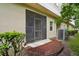 View of the enclosed back patio with sliding screen door, leading to a concrete slab and garden at 1967 Beacon Bay Ct, Apopka, FL 32712