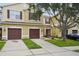 Beautiful townhome featuring a brown two-car garage, tan exterior paint, green grass, and an airy tree at 1967 Beacon Bay Ct, Apopka, FL 32712