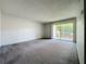 Bright living room featuring neutral walls and carpet, complemented by sliding glass doors to a balcony at 200 St Andrews Blvd # 911, Winter Park, FL 32792