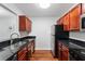 Galley style kitchen with stainless steel appliances, wood floors and dark counters at 2041 Dixie Belle Dr # 2041C, Orlando, FL 32812