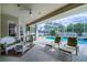 Covered patio with stylish wicker furniture, ceiling fan, and view of the screened-in pool area at 245 Meadow Bay Ct, Lake Mary, FL 32746