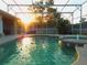 Sparkling pool with screened enclosure offers a private outdoor oasis as the sun sets in the background at 245 Meadow Bay Ct, Lake Mary, FL 32746