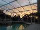 Relaxing pool with tropical landscaping and screen enclosure offers a private outdoor space, as the sun sets at 245 Meadow Bay Ct, Lake Mary, FL 32746