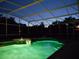 Screened-in pool with a fountain spa, surrounded by lush landscaping, all illuminated in the night at 245 Meadow Bay Ct, Lake Mary, FL 32746