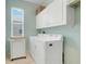 Functional laundry room with a washer, dryer, white cabinets, and a bright window at 3504 Cayugas Loop, St Cloud, FL 34772