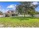 Large backyard features manicured lawn, mature trees, and covered patio at 412 Mallard Way, Kissimmee, FL 34759