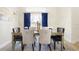 Formal dining room with a glass-top table, elegant chairs, and decorative blue drapes at 412 Mallard Way, Kissimmee, FL 34759