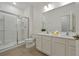 Clean bathroom featuring a glass-enclosed shower, double vanity, and neutral tile flooring at 4429 Ganesha Loop, Kissimmee, FL 34746