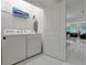 Bright laundry room equipped with modern washer and dryer units, storage shelves, and access to living area at 4429 Ganesha Loop, Kissimmee, FL 34746
