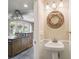 Cozy half bathroom featuring a pedestal sink, decorative mirror, and stylish lighting fixtures at 524 S Lakeview Ave, Winter Garden, FL 34787