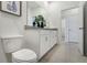 Bright bathroom with white cabinets, granite countertop, and a hallway view at 5909 Cliffbow Loop, Leesburg, FL 34748