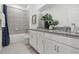 Modern bathroom with a double sink vanity, granite countertop, bathtub, and neutral tile at 5909 Cliffbow Loop, Leesburg, FL 34748