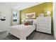 Bright bedroom with a white bed, an accent wall, a dresser and a window overlooking a green yard at 5909 Cliffbow Loop, Leesburg, FL 34748