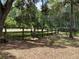 View of the wooded property featuring mature trees, fenced perimeter, and an Emu at 63 Lake Wood Cir, Ocala, FL 34482