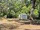 View of the shed on the wooded property featuring mature trees and leaf-covered ground at 63 Lake Wood Cir, Ocala, FL 34482
