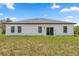 Rear exterior view of the home with a grassy yard, sliding glass doors, and multiple windows at 6765 152Nd Lane Rd, Ocala, FL 34473