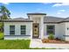 Close up of the front of the house with a wood front door, neutral paint, and a well manicured lawn at 6765 152Nd Lane Rd, Ocala, FL 34473