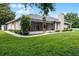 The backyard has a screened-in lanai, mature trees, a chimney, and a well-maintained lawn at 707 Heritage Ne Dr, Winter Haven, FL 33881