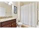 Well-lit bathroom featuring granite counters, vanity, and a shower with a white curtain, providing a functional space at 7409 Fairgrove Ave, Windermere, FL 34786
