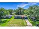 Aerial view of blue home with green lawn, red door and mature trees, showcasing its curb appeal at 91 High St, Winter Haven, FL 33880