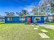Quaint blue home features a manicured lawn, a charming walkway, and a vibrant red front door at 91 High St, Winter Haven, FL 33880