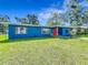 Charming blue single-story home boasts a manicured lawn, mature landscaping, and a bright red front door at 91 High St, Winter Haven, FL 33880