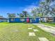 Charming blue home with a bright red door and a well-manicured lawn, set beneath a beautiful blue sky at 91 High St, Winter Haven, FL 33880