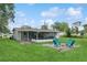 Grassy backyard showing the home's screened-in porch with an exterior patio featuring four colorful chairs at 941 Grey Oak Ct, Orlando, FL 32809