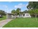 Well-maintained home featuring a covered parking area, lush lawn, and neatly arranged potted plants at 941 Grey Oak Ct, Orlando, FL 32809