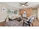 Bright living room featuring an exposed brick wall, neutral furniture, a ceiling fan, and a large window at 941 Grey Oak Ct, Orlando, FL 32809