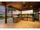 Covered outdoor kitchen featuring stone counters, stainless steel appliances, and stunning lake views at 4318 Waterfront Pkwy, Orlando, FL 32806