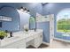 Bathroom featuring double sinks, black hardware, and walk-in shower with a marble wall at 1161 Roxboro Rd, Longwood, FL 32750